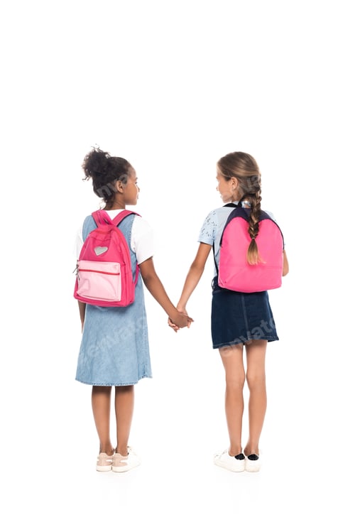 Preview: back view of multicultural schoolgirls with backpacks holding hands and standing isolated on white