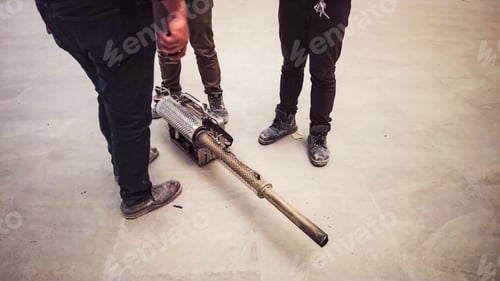 Preview: Thermal fogging machine on the floor with unidentified workers standing near it.
