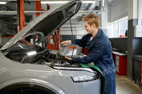 Preview: Auto mechanic pouring fresh oil into car engine from plastic container