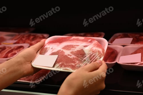 Preview: Woman taking packed pork meat from shelf in supermarket