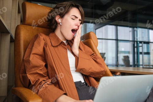 Preview: Portrait of tired office worker, sits in conference room with laptop, yawns, feels tired
