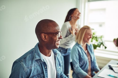 Preview: Young African businessman laughing with colleagues in an office