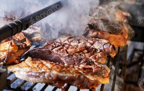 Preview: Grilled steaks and ribs cooking on barbecue