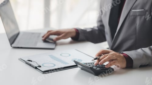 Preview: Businessman using a calculator to calculate numbers on a company's financial documents, she is analy