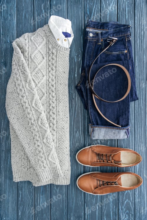 Preview: Flat lay with knitted sweater, jeans and brown shoes on wooden background