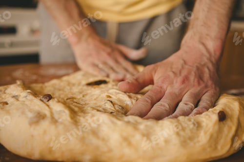 Preview: male hands kneading dough with raisins for Easter cake