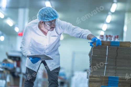Preview: A food processing supervisor in protective gear inspecting packaging