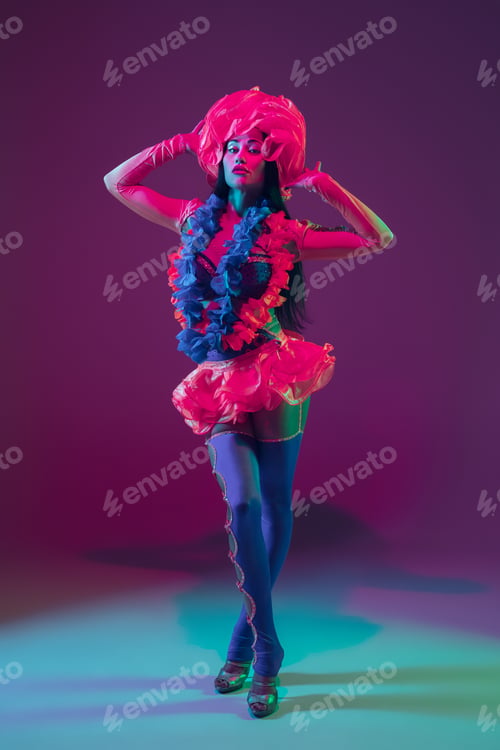 Preview: Attractive hawaiian brunette model on purple studio background in neon light