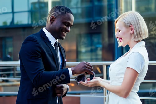 Preview: handsome Afro businessman in a stylish black suit gives car keys