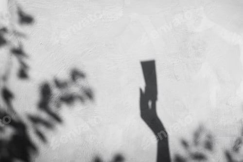 Preview: Shadow from a woman's hand holding a tube of body care.