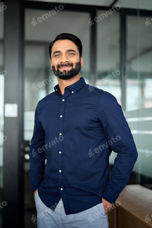 Preview: Happy confident Indian business man standing in office, vertical portrait.