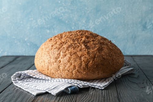 Preview: Bread on kitchen towel on wooden table against light background, space for text