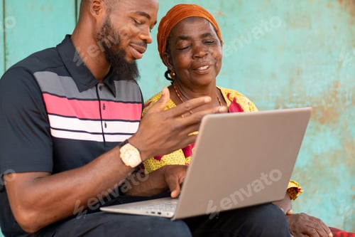 Preview: young african man using a laptop with an old african woman