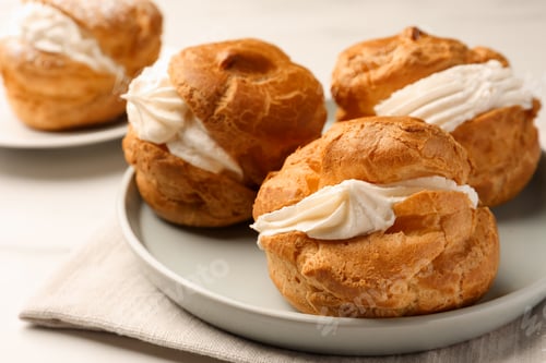 Preview: Delicious profiteroles with cream filling on table, closeup