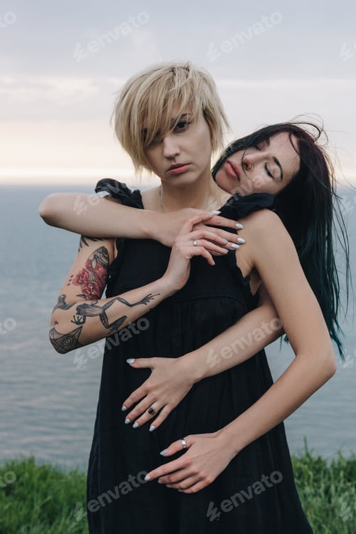 Preview: beautiful young women embracing in front of ocean on cloudy day