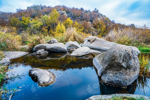 Preview: A fast clean stream runs among smooth wet stones surrounded by tall dry lumps