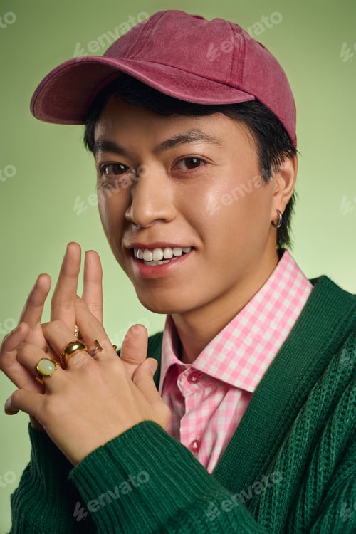 Preview: Stylish Asian man poses confidently in vibrant green studio space
