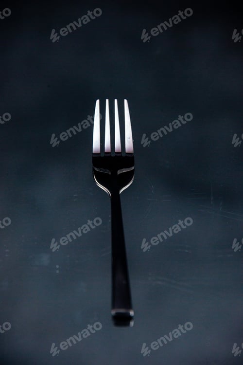 Preview: Overhead view of elegant shiny metal fork on black wave background with free space