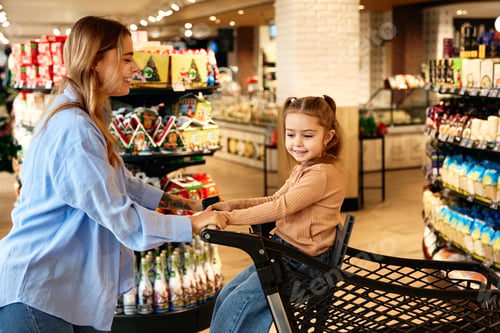 Preview: Happy mother shopping with daughter in supermarket during holiday season