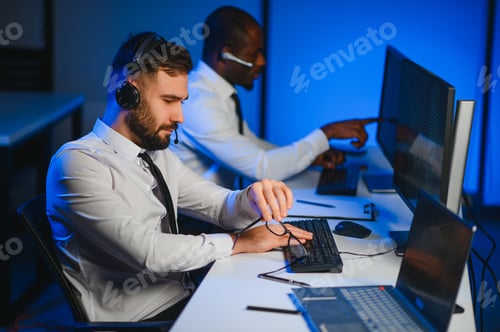 Preview: Male Data Scientist Works on Personal Computer Wearing a Headset in Big Infrastructure Control
