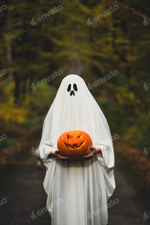 Preview: Ghostly figure with pumpkin in enchanted a forest on a moody autumn day.