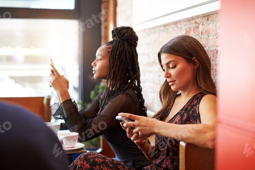 Preview: Female Customers Using Mobile Phones Sitting In Coffee Shop