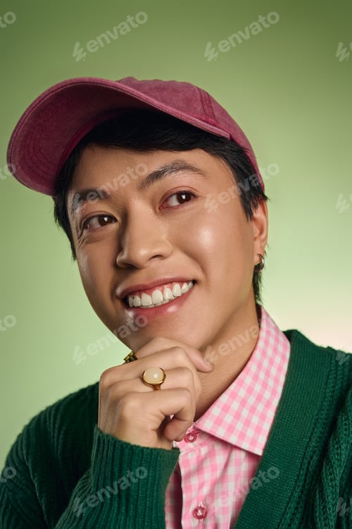 Preview: Stylish Asian man in green studio showcases trendy fashion with cheerful smile