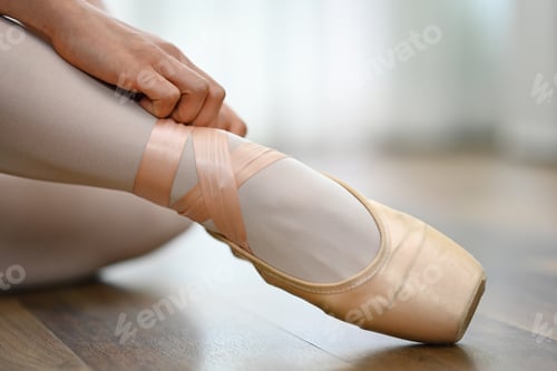 Preview: Close up ballerina tying pointe shoes in dance studio. Art, dance, people and inspiration concept