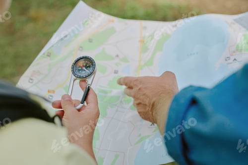 Preview: Young Adult Man Navigating Outdoors Using Compass and Paper Map