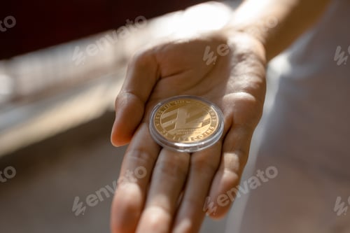 Preview: Young man holding LTC Lite coin on palm of hand