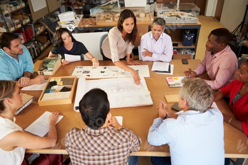 Preview: Female Boss Leading Meeting Of Architects Sitting At Table