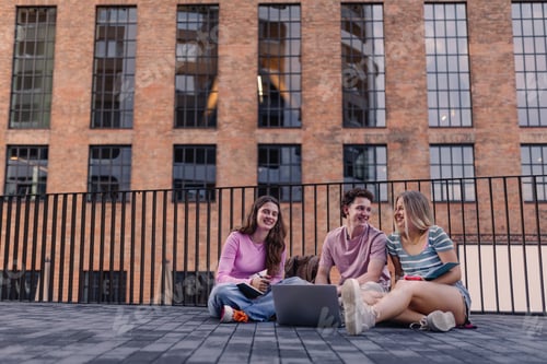 Preview: Young stylish generation Z students sitting in front of school building.