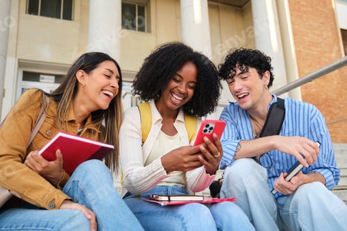 Preview: Diverse university students laughing using smartphone on campus stairs