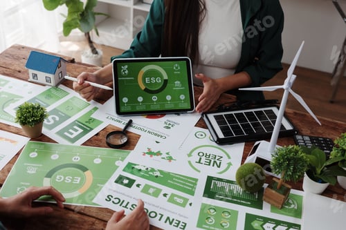 Preview: Businesswoman pointing at ESG report displayed on tablet during a meeting about net zero target