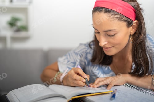 Preview: Young woman, highlighting her college book, sitting in her office.