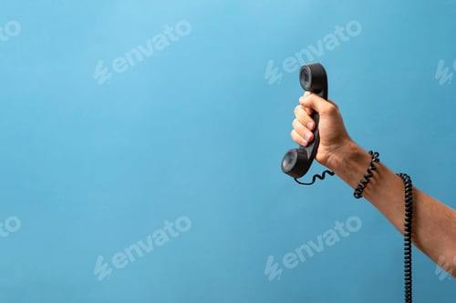 Preview: a creative idea of hand holding old vintage telephone handset with cablw