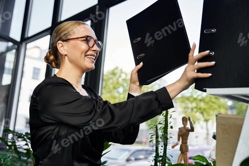 Preview: Young beautiful plus size woman joyfully organizing files in a bright office during work hours