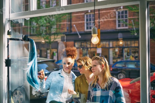 Preview: View through glass of women looking in shop window