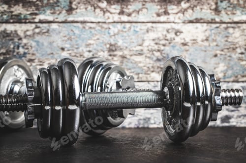 Preview: Iron dumbbells before old wooden wall.