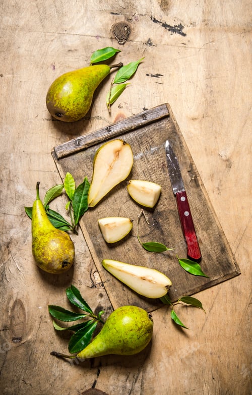 Preview: Sliced pears on old chopping board with leaves .