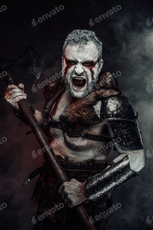 Preview: Screaming mythical warrior with painted skin and axe in studio