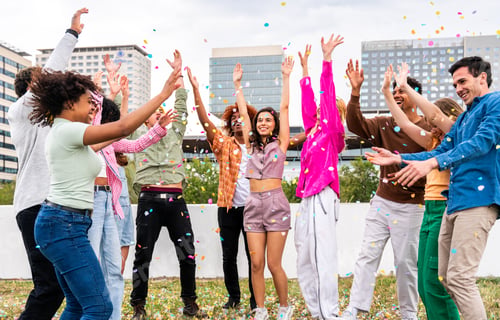 Preview: Happy playful multiethnic group of young friends bonding outdoors