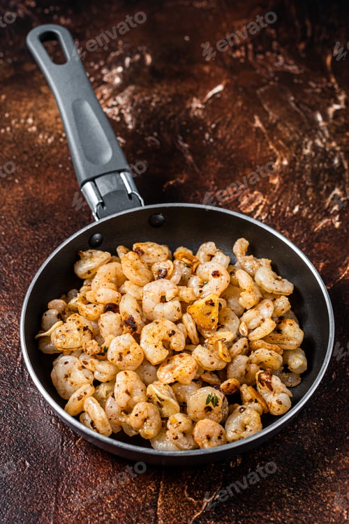 Preview: Fried peeled Shrimps prawns with garlic, olive oil in a skillet. Dark background. top view