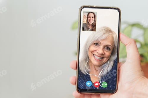 Preview: Happy senior and daughter talking on video call with mobile phone - Focus on hand holding smartphone
