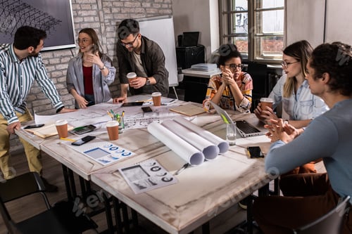 Preview: Group of modern business people in casual wear discussing architectural designs.