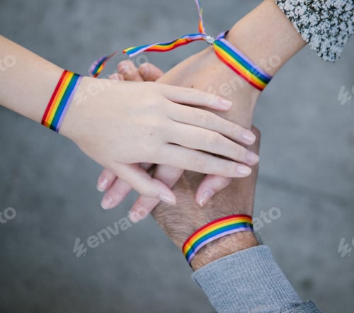 Preview: Homosexual people in rainbow bracelets stacking hands