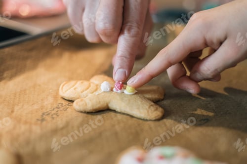 Preview: Two hands apparently mother and daughter decorating a Christmas cookie