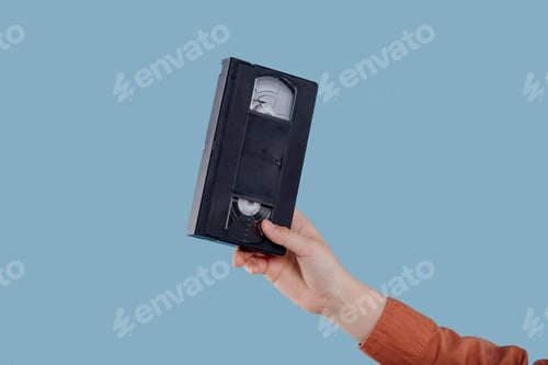 Preview: Video tape cassette (VHS) with blue label hold by child hand
