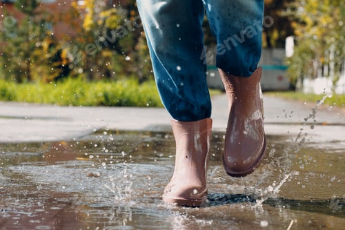 Preview: Woman wearing rain rubber boots walking running and jumping into puddle