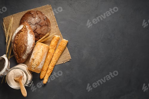 Preview: Various types of breads and buns from the bakery on black stone background.